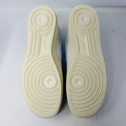 Introducing the Nike Air Force 1 Low Kith Hawaii sneaker: a fresh white design with white laces, light blue inner lining, teal swoosh, textured pattern, and cream-colored sole. Packaged in a gray shoebox, it features the word AIR embossed on the side.