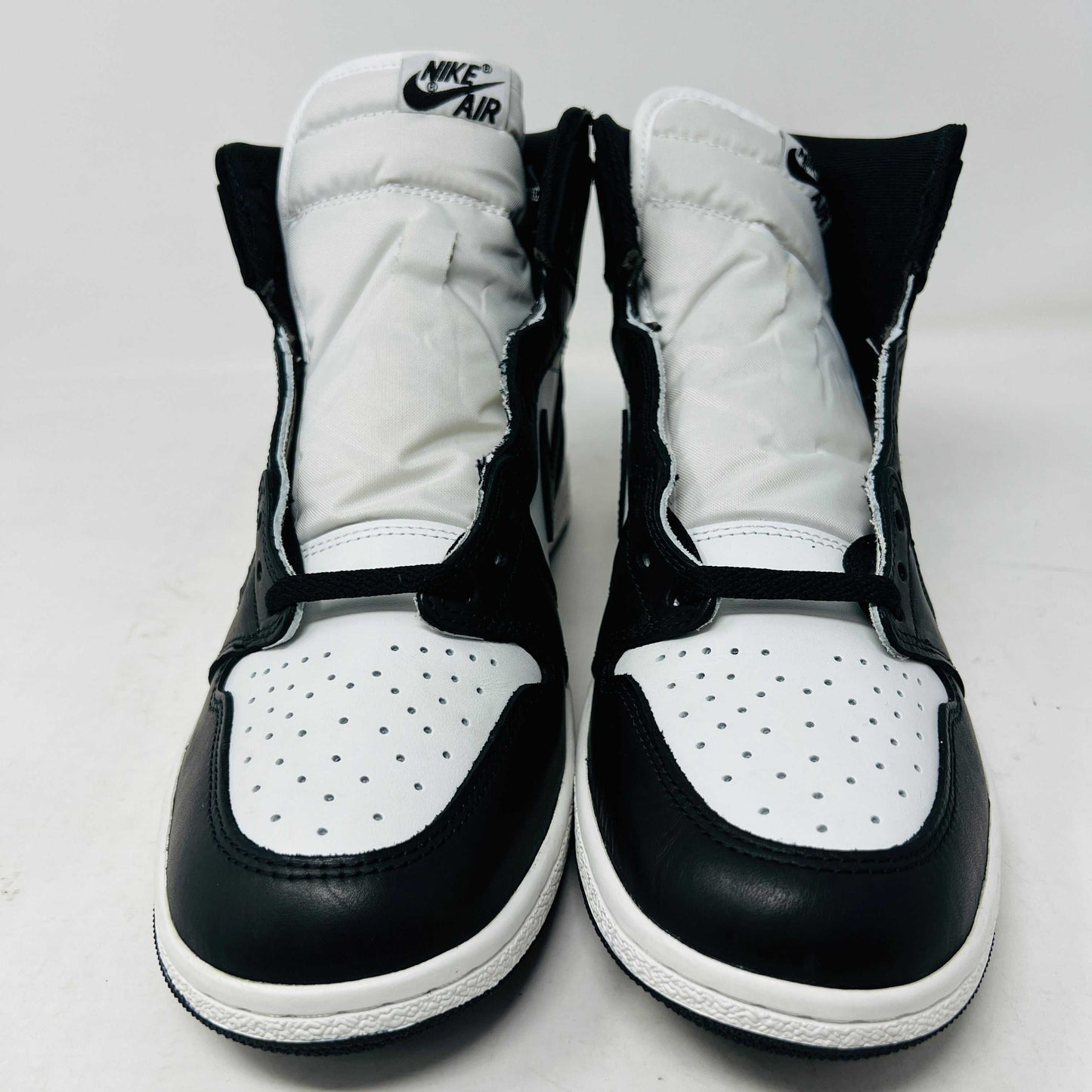 A Jordan 1 Retro High 85 Black White (2023) sneaker is showcased on a red Nike box. This black and white high-top features the Air Jordan logo and includes extra white laces.