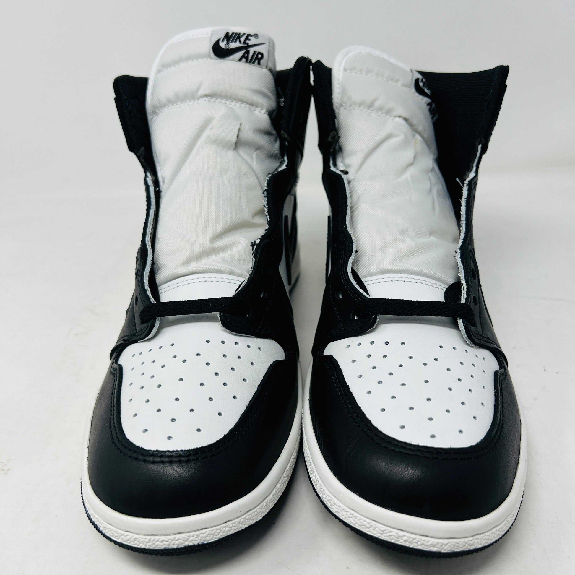 A Jordan 1 Retro High 85 Black White (2023) sneaker is showcased on a red Nike box. This black and white high-top features the Air Jordan logo and includes extra white laces.