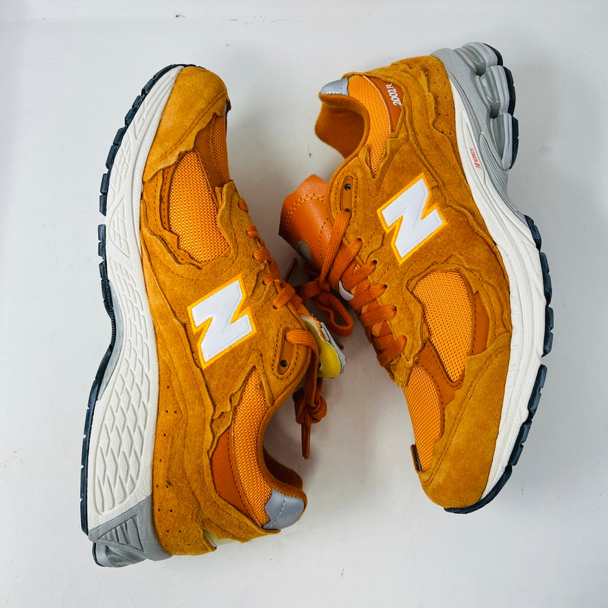 Brand new New Balance 2002R Protection Pack sneakers in Vintage Orange sit on their box, featuring a suede and mesh design, white N logo on sides, gray and white sole. Box in pristine condition with label for mens size 10.5, UK size 9.5.