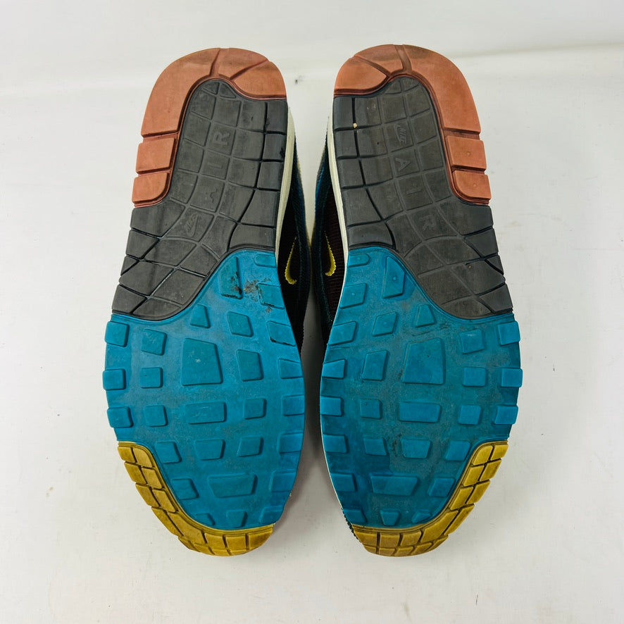 The Nike Air Max 1/97 Sean Wotherspoon sneakers showcase a colorful upper with hues of yellow, blue, and pink. They include extra blue and white laces and come in a red box labeled with size 9.5.