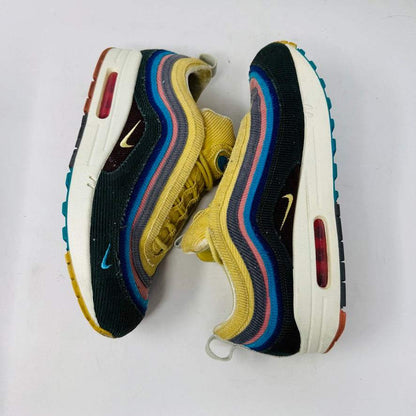 The Nike Air Max 1/97 Sean Wotherspoon sneaker, featuring a multicolored wave-like design, rests on a New Balance box and includes extra blue, white, and dark blue laces. It showcases an authentic air cushion in the sole.