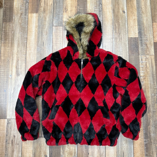 The preowned Supreme Diamond Faux Fur Jacket in red, featuring a red and black diamond pattern with brown faux fur trim on the hood, perfectly blends style and comfort. Its stylishly shown on a wooden floor.