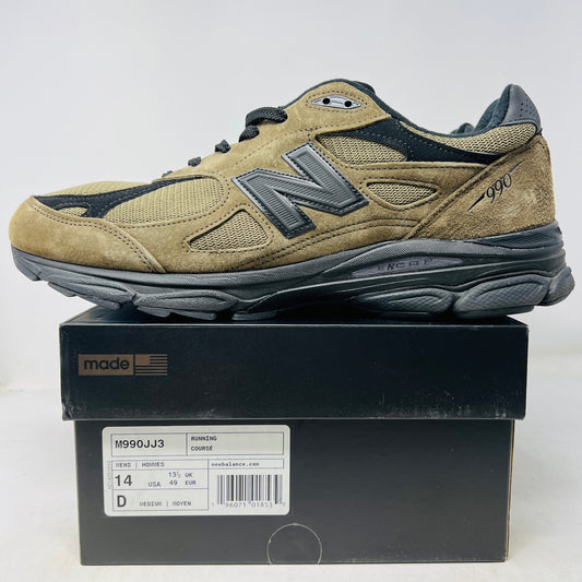 The New Balance 990v3 MiUSA JJJJound Brown Black athletic shoe, released in 2022, features tan and black mesh-suede uppers with an N logo on the side and 990 on the heel. It sits atop a black shoebox with the label M990JJ3 and shows light wear.