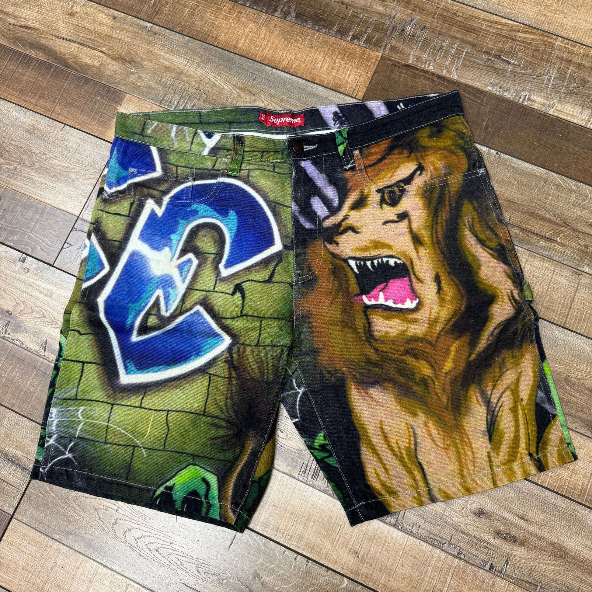 Supreme Lion's Den Painter Shorts with graffiti and lion design, preowned.
