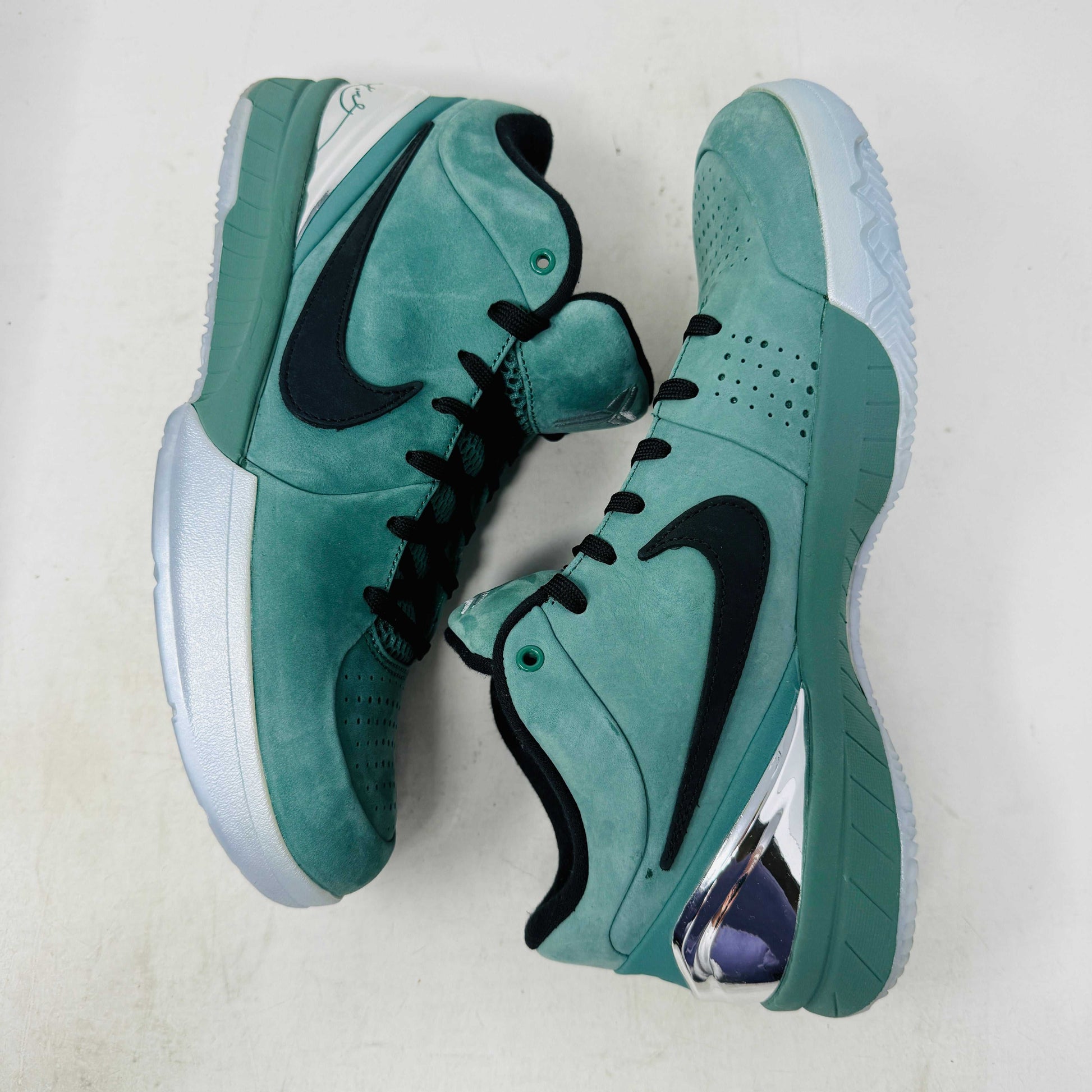 Green Nike Kobe 4 Protro Girl Dad basketball shoe with a black swoosh, silver heel accent, and suede finish sits atop a Nike shoebox. In 9/10 condition and worn once, the label indicates size 9.5 US with additional sizing details for these authentic shoes.