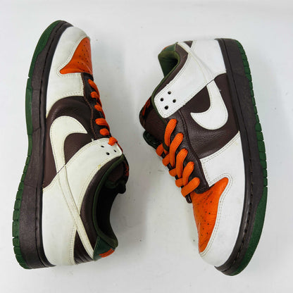 The Nike SB Dunk Low Oompa Loompa sneaker, in a brown, white, and orange color scheme with clean uppers, is displayed on its size 9.5 box. In the foreground is a packet of white laces with a Nike logo—guaranteed 100% authentic.