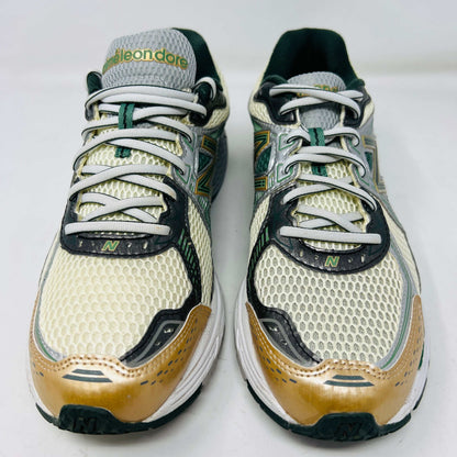 The New Balance 860v2 Aime Leon Dore Green sneaker, with mesh and leather uppers, features green and beige accents. Displayed on its box, it comes with cream and yellow laces for an authentic look.