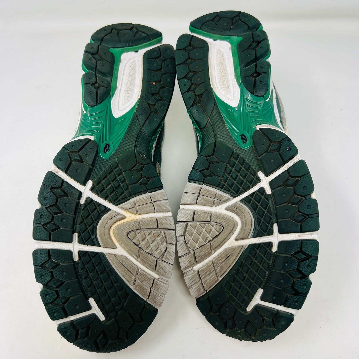 The New Balance 860v2 Aime Leon Dore Green sneaker, with mesh and leather uppers, features green and beige accents. Displayed on its box, it comes with cream and yellow laces for an authentic look.