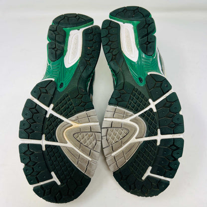 The New Balance 860v2 Aime Leon Dore Green sneaker, with mesh and leather uppers, features green and beige accents. Displayed on its box, it comes with cream and yellow laces for an authentic look.