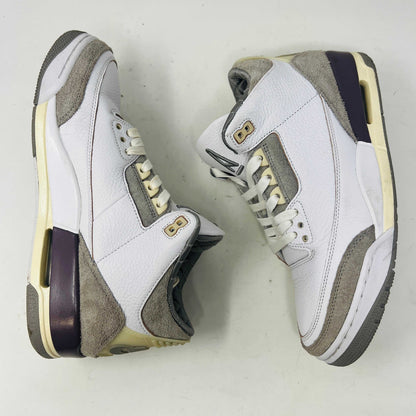 The Holy Ground Jordan 3 Retro SP A Ma Maniére (Womens) sneakers in white and gray, priced at $450, are displayed atop their box. They feature textured leather, suede accents, and include a pack of cream-colored extra laces for customization.