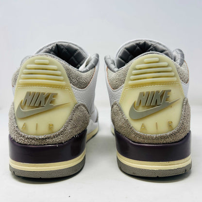 The Holy Ground Jordan 3 Retro SP A Ma Maniére (Womens) sneakers in white and gray, priced at $450, are displayed atop their box. They feature textured leather, suede accents, and include a pack of cream-colored extra laces for customization.