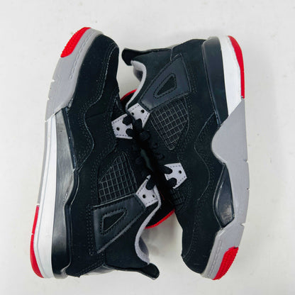 The Jordan 4 Retro Bred (2019) (PS) in black and red, featuring clean uppers with a white midsole and gray accents, sits on its original black shoebox. The box displays size, product details, and the iconic Jumpman logo, underscoring these authentic shoes from Jordans 2019 collection.