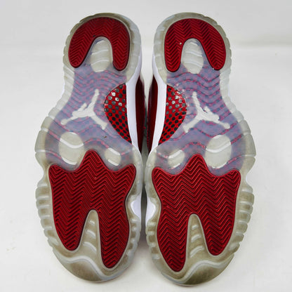 The Jordan 11 Retro Cherry (2022) is a red and white high-top sneaker with glossy red patent leather on the toe, clean mesh uppers, striking red accents, pristine white laces, a visible air sole unit, and the authentic Jumpman logo. Its in impeccable condition after being worn once.