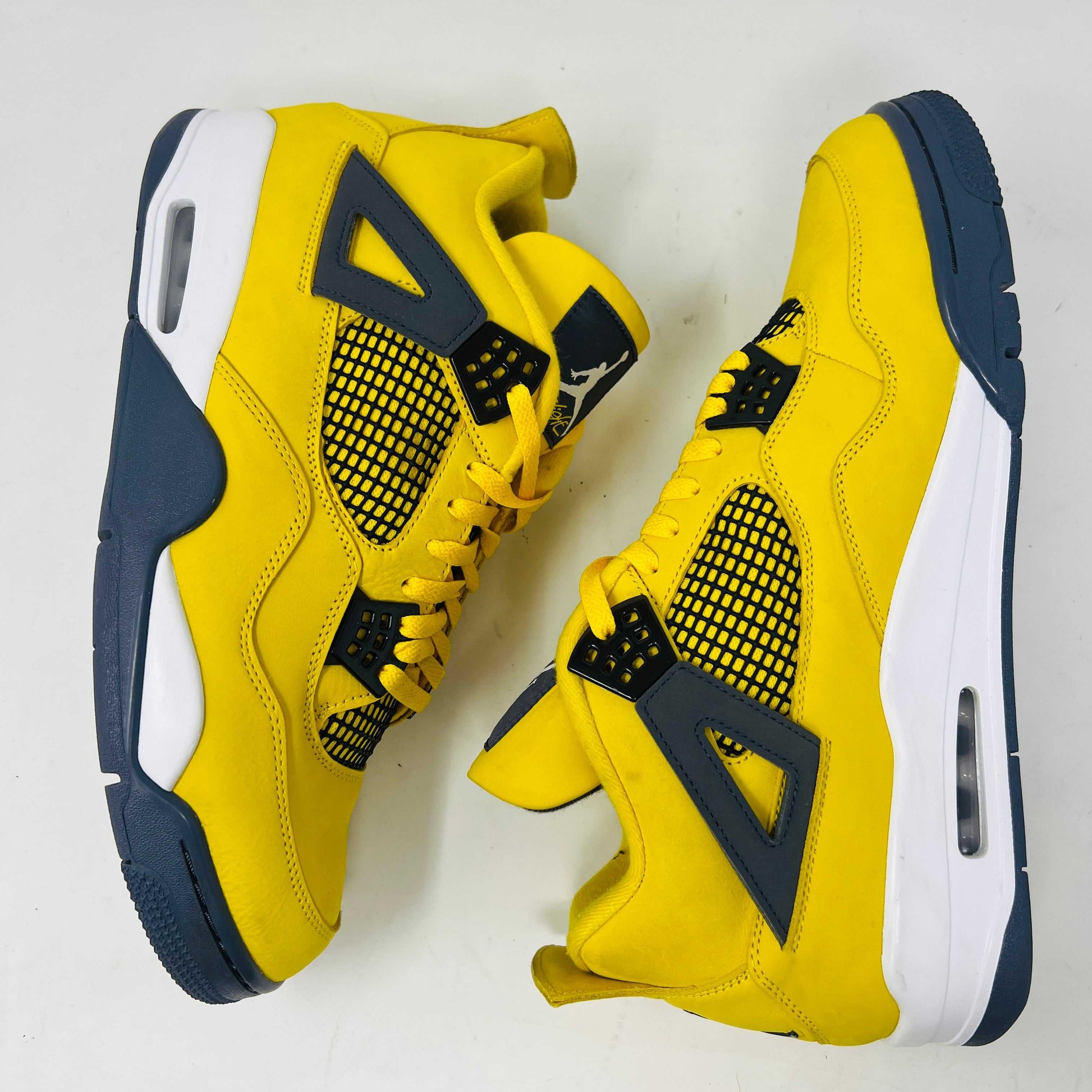 The Jordan 4 Retro Lightning (2021) in yellow rests on its matching box with a size label. Featuring clean uppers, blue accents, a visible air unit in the heel, and a black Jumpman logo on the box, note that returns are not accepted.
