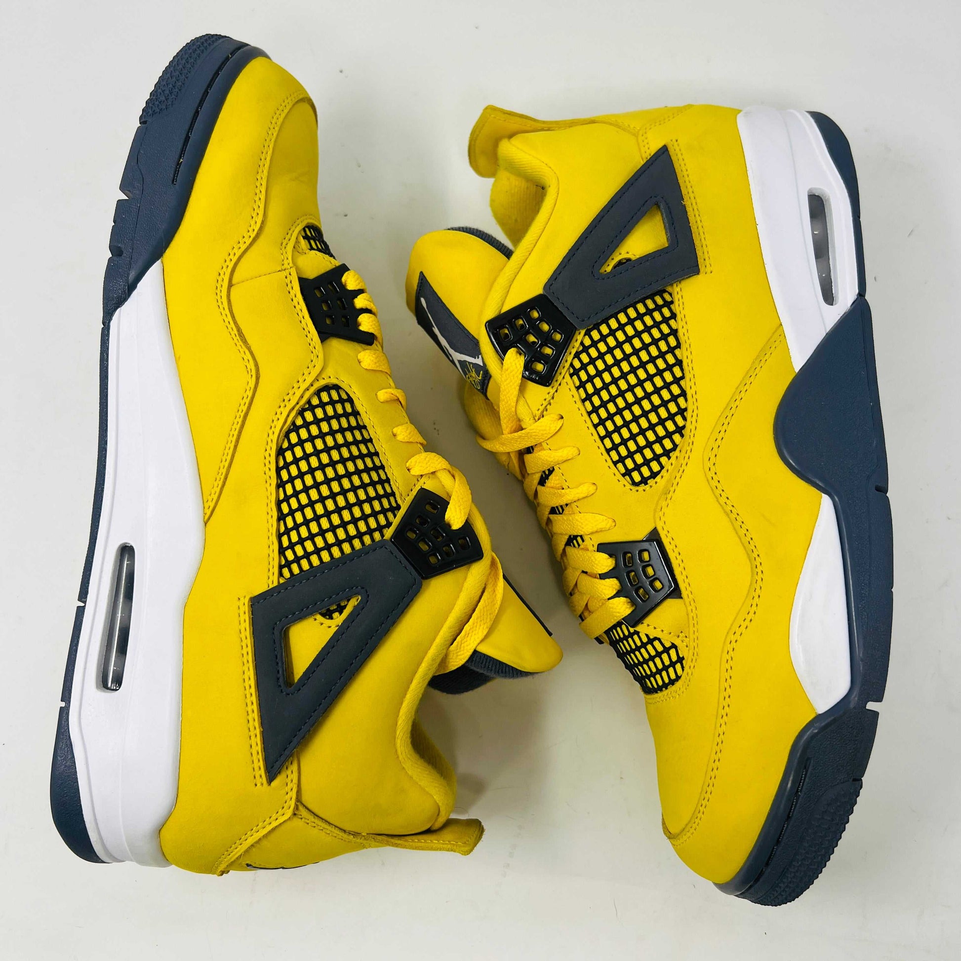 The Jordan 4 Retro Lightning (2021) in yellow rests on its matching box with a size label. Featuring clean uppers, blue accents, a visible air unit in the heel, and a black Jumpman logo on the box, note that returns are not accepted.