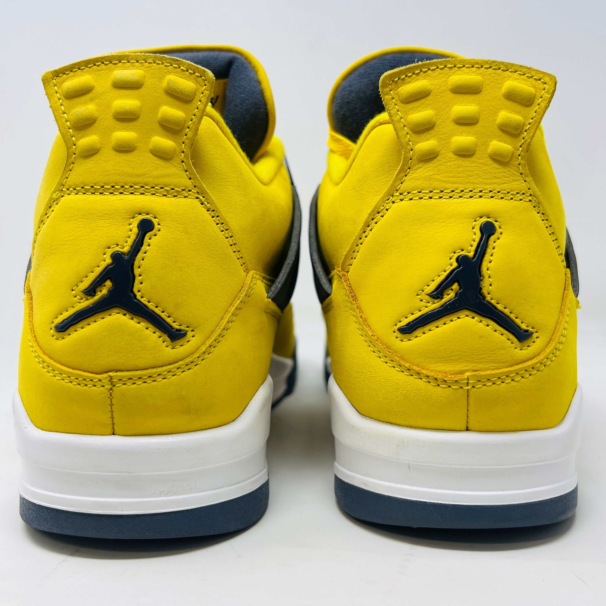 The Jordan 4 Retro Lightning (2021) in yellow rests on its matching box with a size label. Featuring clean uppers, blue accents, a visible air unit in the heel, and a black Jumpman logo on the box, note that returns are not accepted.
