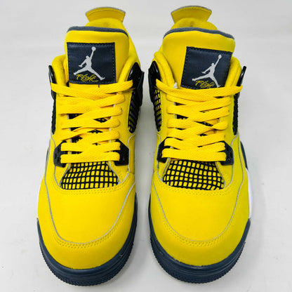 The Jordan 4 Retro Lightning (2021) (GS) sneaker, in bright yellow with black/gray accents and a visible air unit, is displayed on its matching shoebox. Both the box and heel sport the iconic Jumpman logo, with size details confirming authenticity from the Jordan brand.