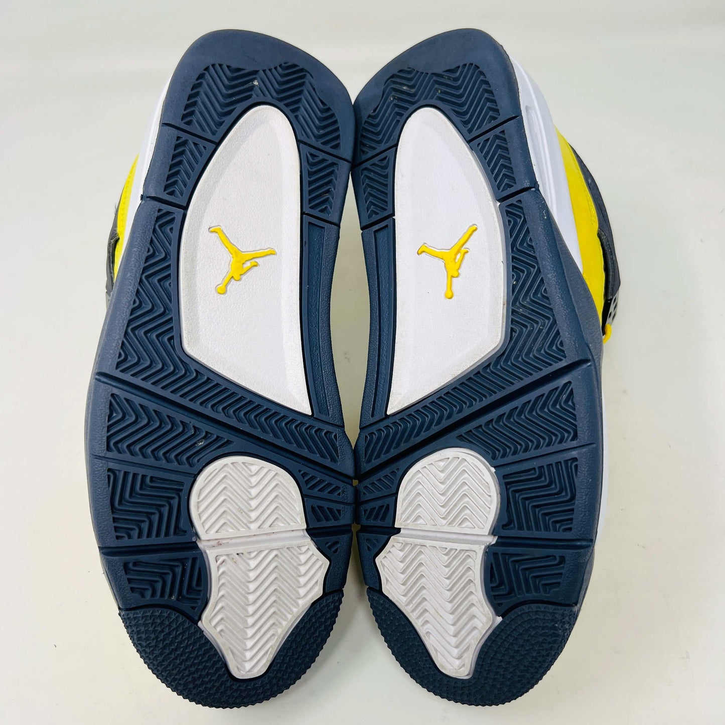 The Jordan 4 Retro Lightning (2021) (GS) sneaker, in bright yellow with black/gray accents and a visible air unit, is displayed on its matching shoebox. Both the box and heel sport the iconic Jumpman logo, with size details confirming authenticity from the Jordan brand.