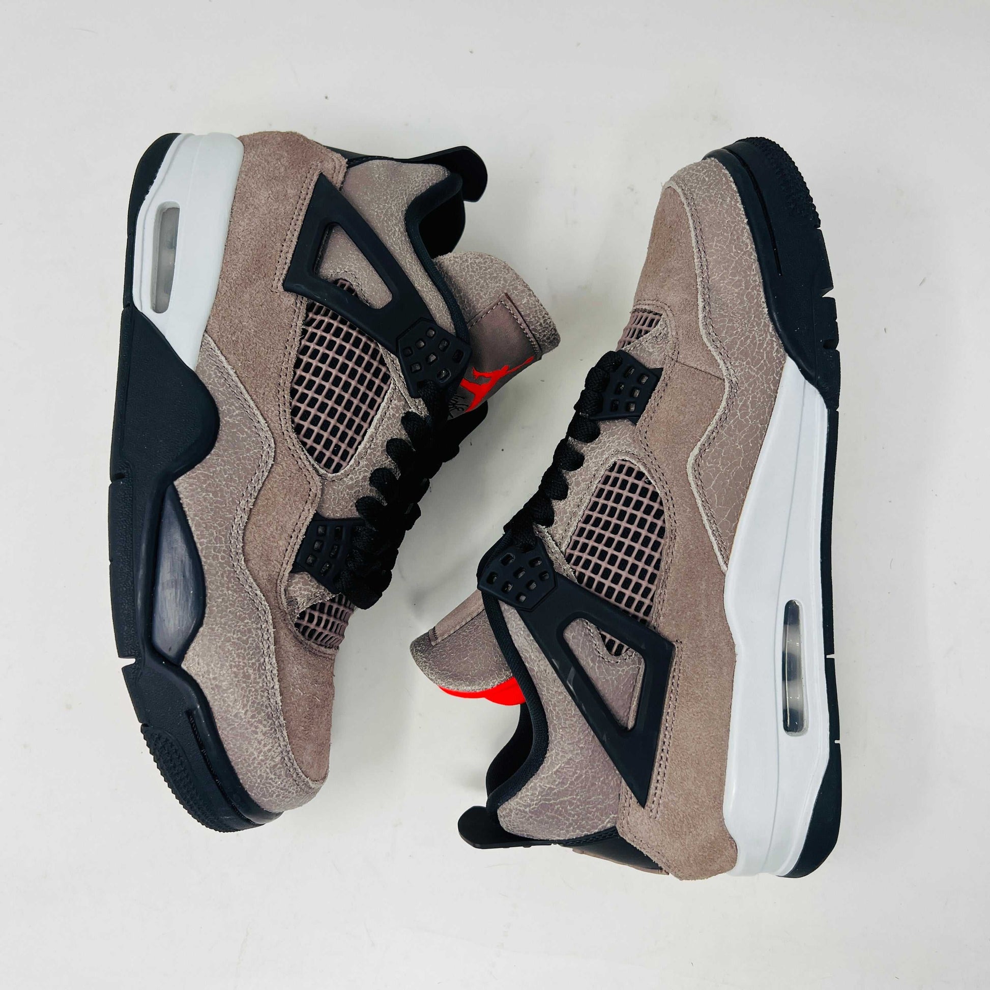 The Jordan 4 Retro Taupe Haze sneaker is showcased on its speckled brown shoebox. Released in 2021, it boasts black mesh accents, a visible air unit, and the Jumpman logo on the tongue. Size and style details are printed on the box.
