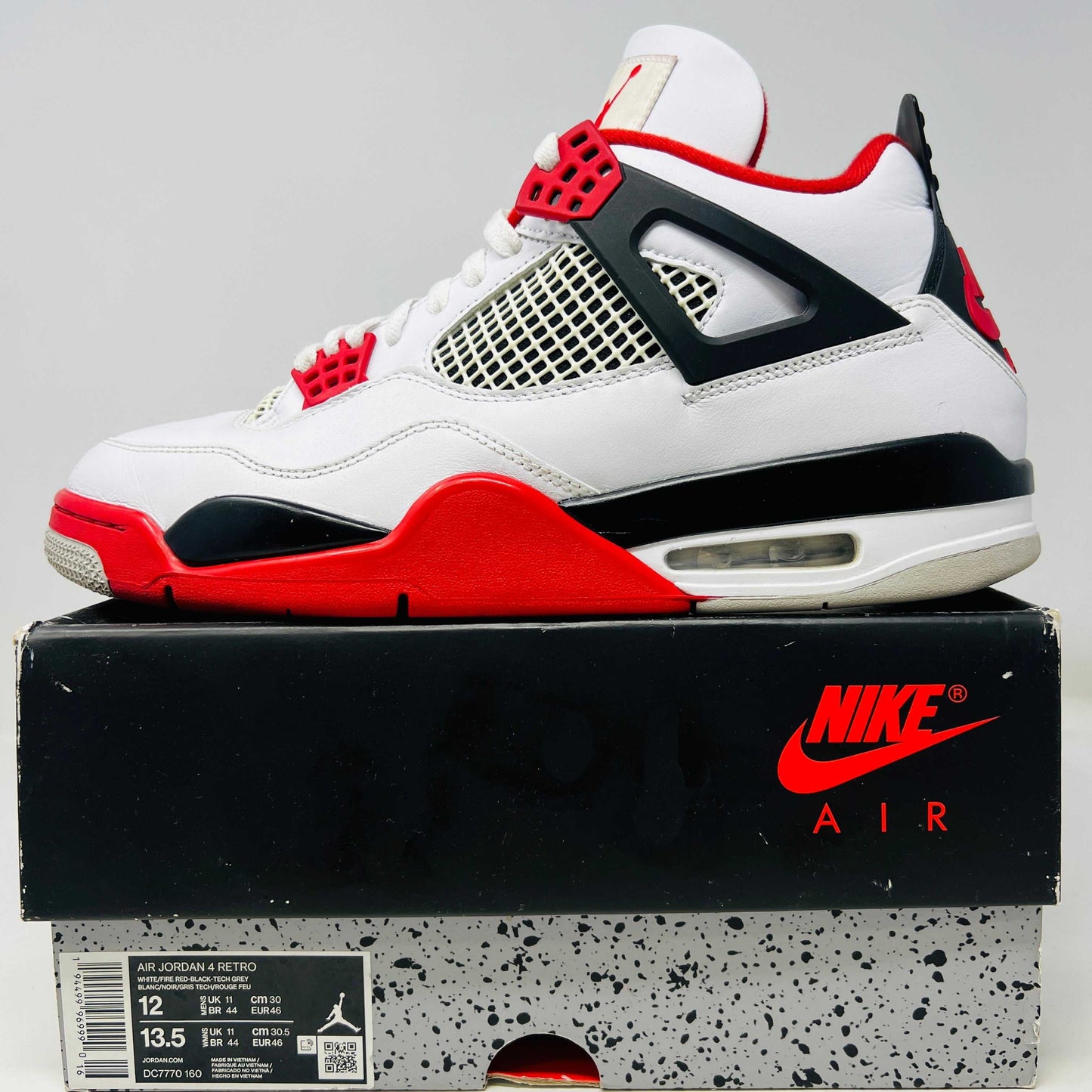 Jordan 4 Retro Fire Red 2020 sneaker on shoebox, clean uppers, slight wear, Nike Air branding.