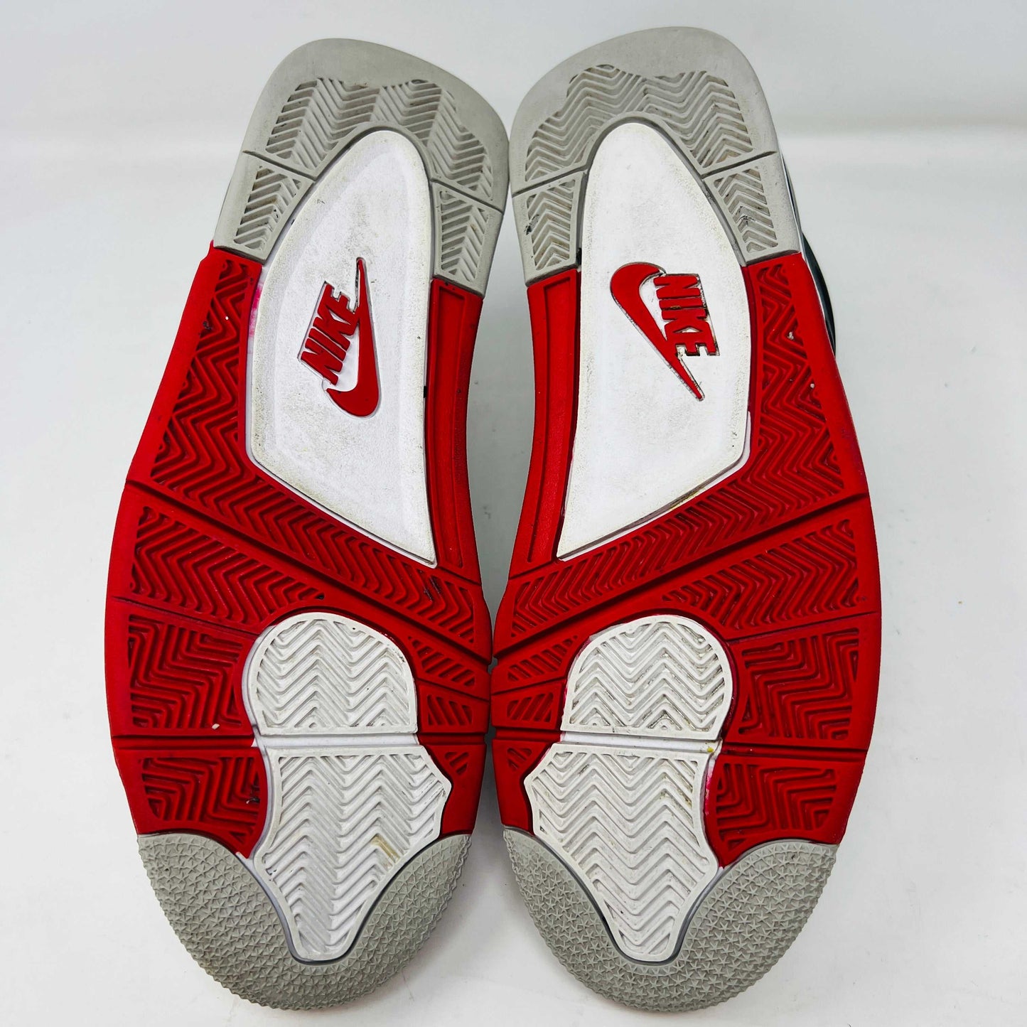 The Jordan 4 Retro Fire Red (2020) sneaker features a white leather upper with red accents, black netting, and a visible Air unit. It rests atop a matching Nike Air branded shoebox, with branding also on the shoe heel.