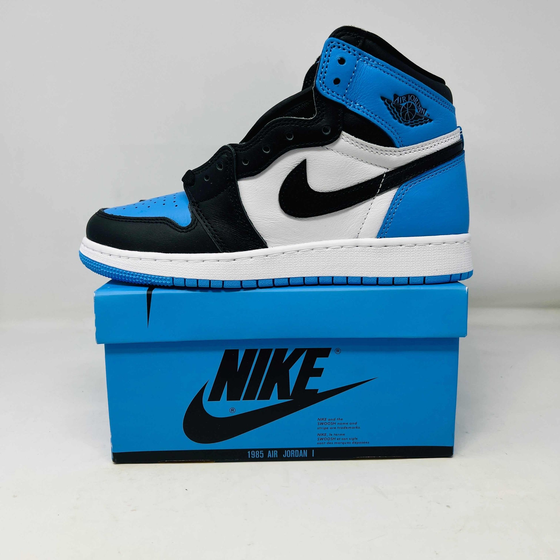 Jordan 1 Retro High OG UNC Toe (GS) sneakers in black, white, and blue on Nike box.