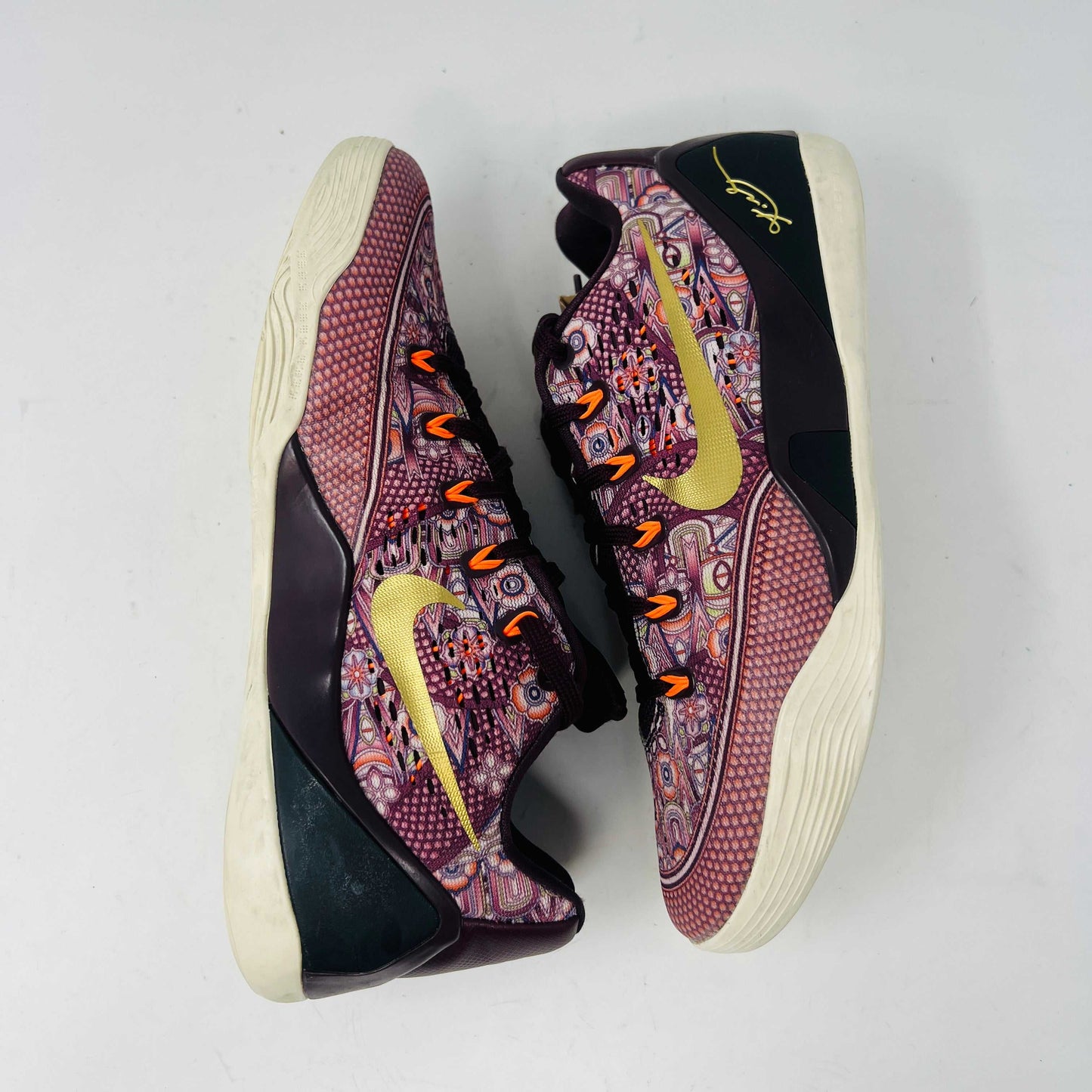 The Nike Kobe 9 EM Low Silk sneaker, featuring a colorful pattern with red and purple hues and a gold swoosh, rests on its box. Priced at $140 for size 9, this pair has slight normal wear adding character.