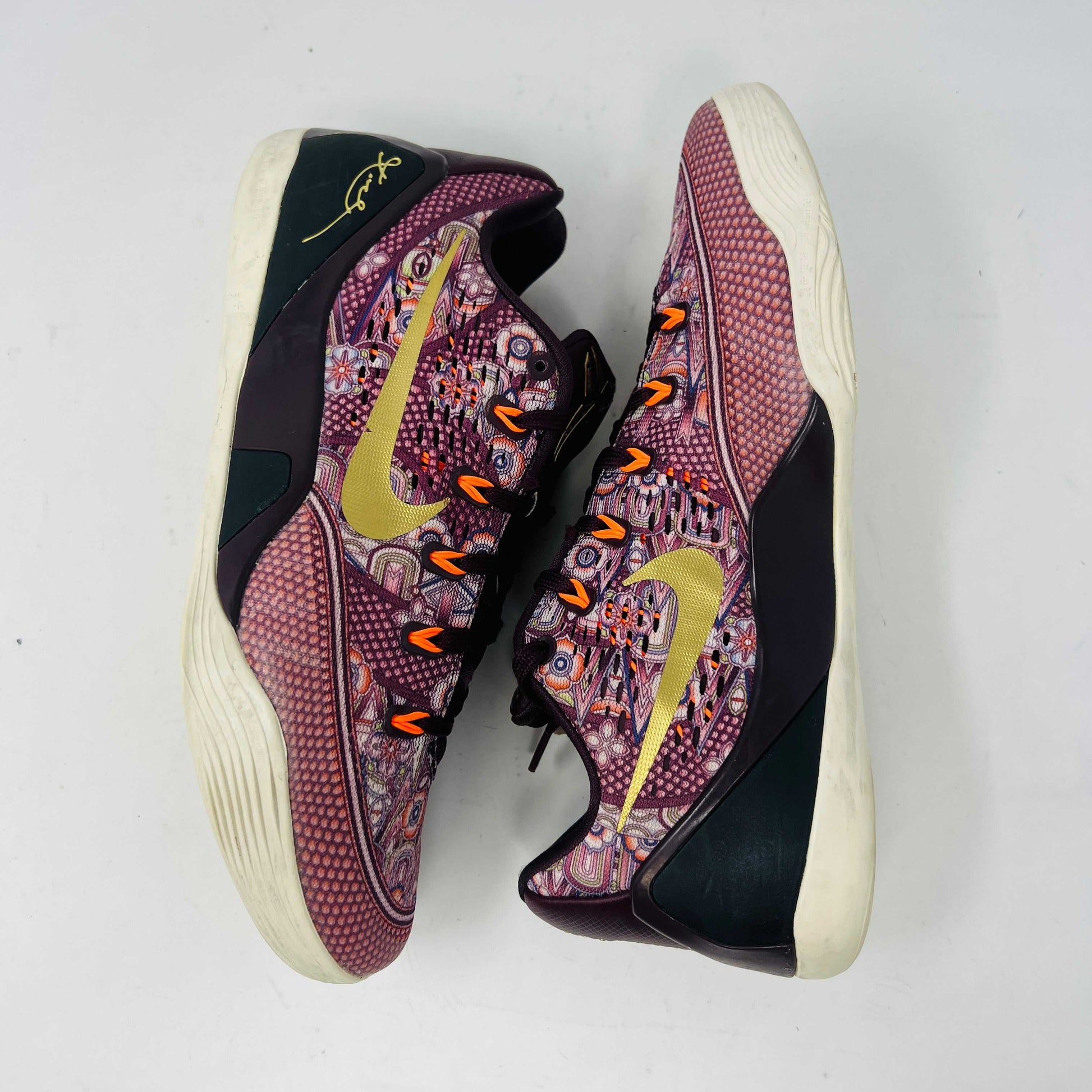 The Nike Kobe 9 EM Low Silk sneaker, featuring a colorful pattern with red and purple hues and a gold swoosh, rests on its box. Priced at $140 for size 9, this pair has slight normal wear adding character.