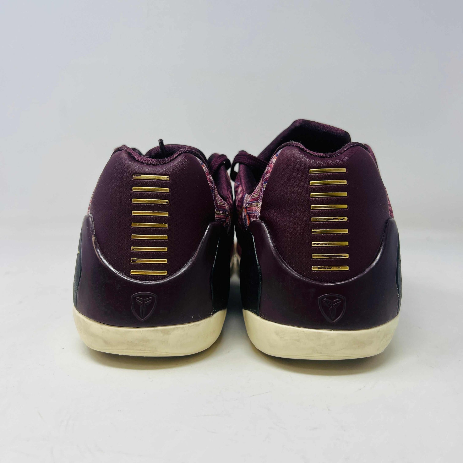 The Nike Kobe 9 EM Low Silk sneaker, featuring a colorful pattern with red and purple hues and a gold swoosh, rests on its box. Priced at $140 for size 9, this pair has slight normal wear adding character.