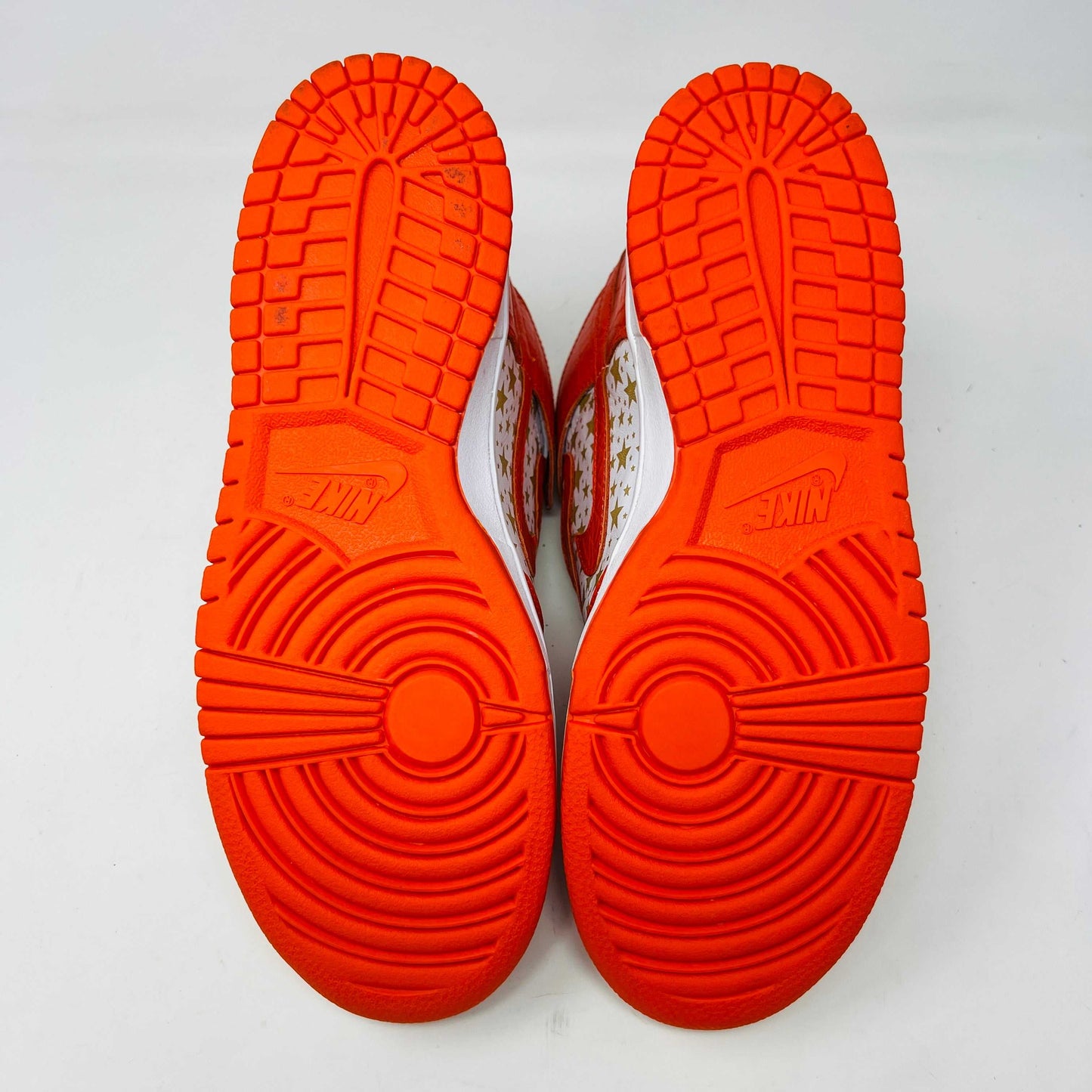 The Nike Dunk High Pro SB Supreme Orange Stars sneaker features an orange and white color scheme with star patterns on the side, a textured finish, and comes with authentic orange and white laces in a separate package.