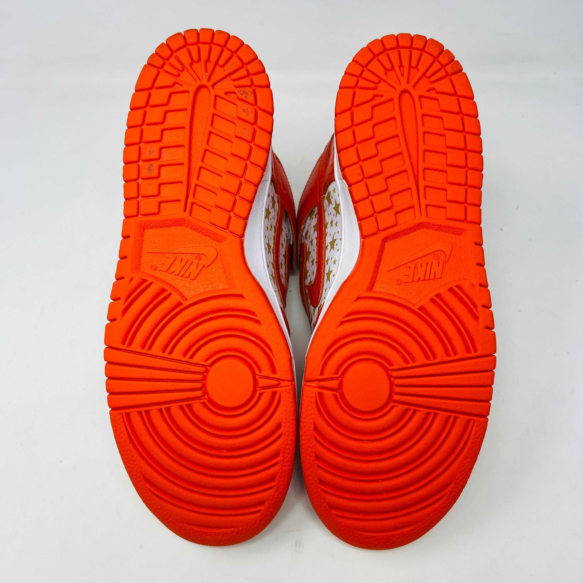 The Nike Dunk High Pro SB Supreme Orange Stars sneaker features an orange and white color scheme with star patterns on the side, a textured finish, and comes with authentic orange and white laces in a separate package.