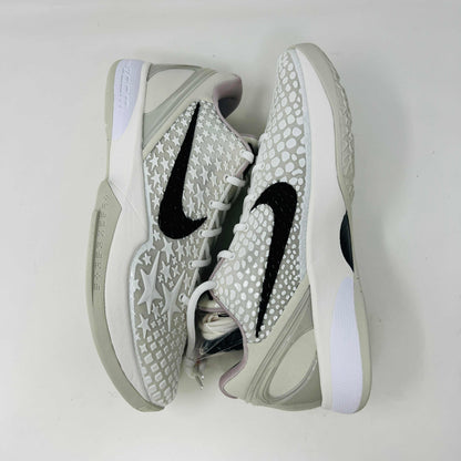 The Nike Kobe 6 Protro Sail All-Star shoes, featuring white textured patterns and black swoosh details with star designs, are elegantly displayed on a sleek black shoebox.