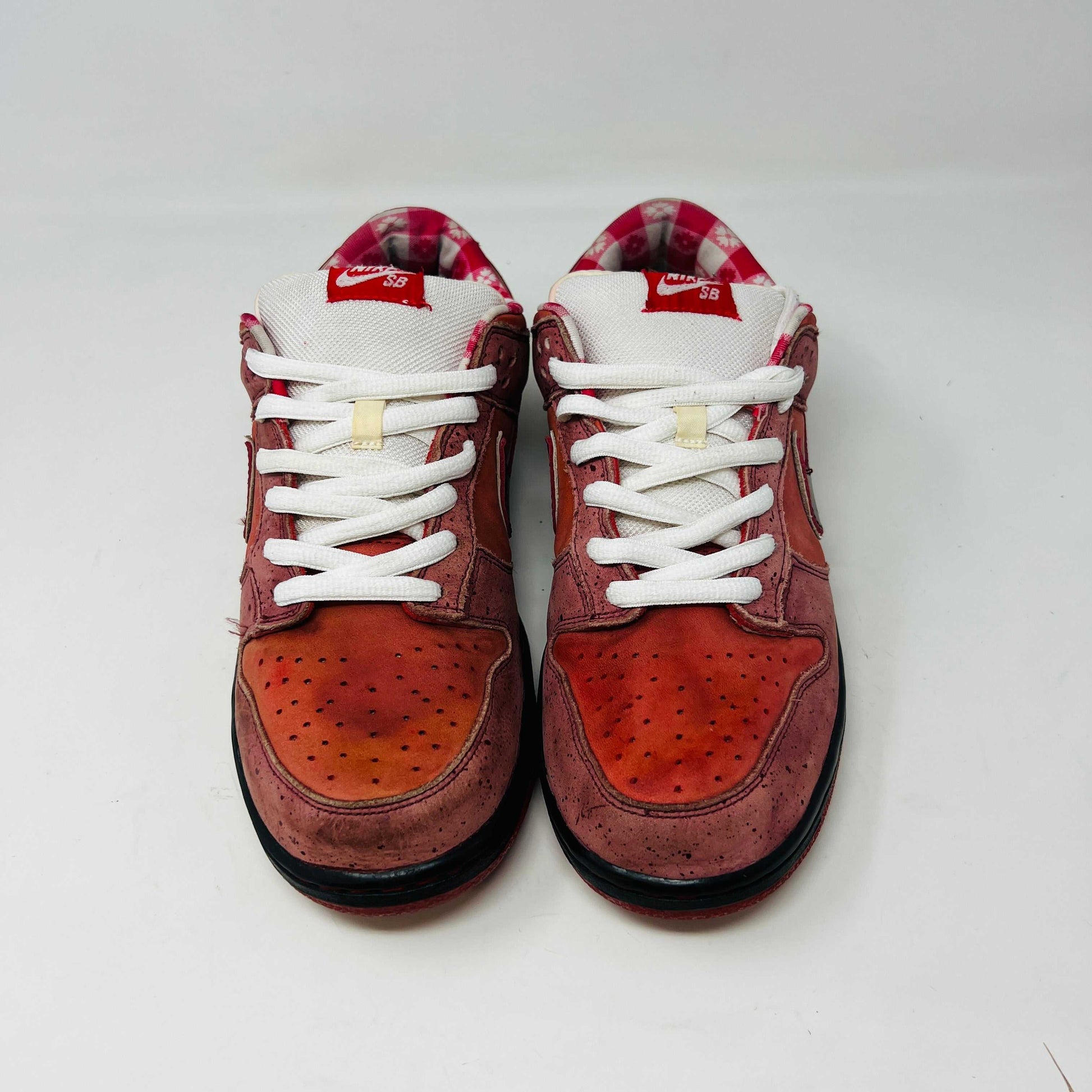 The authentic 2008 Nike SB Dunk Low Concepts Red Lobster features a striking red and pink design with a dark swoosh, complemented by white laces and red accents. It comes in a speckled gray and black replacement box for added flair.