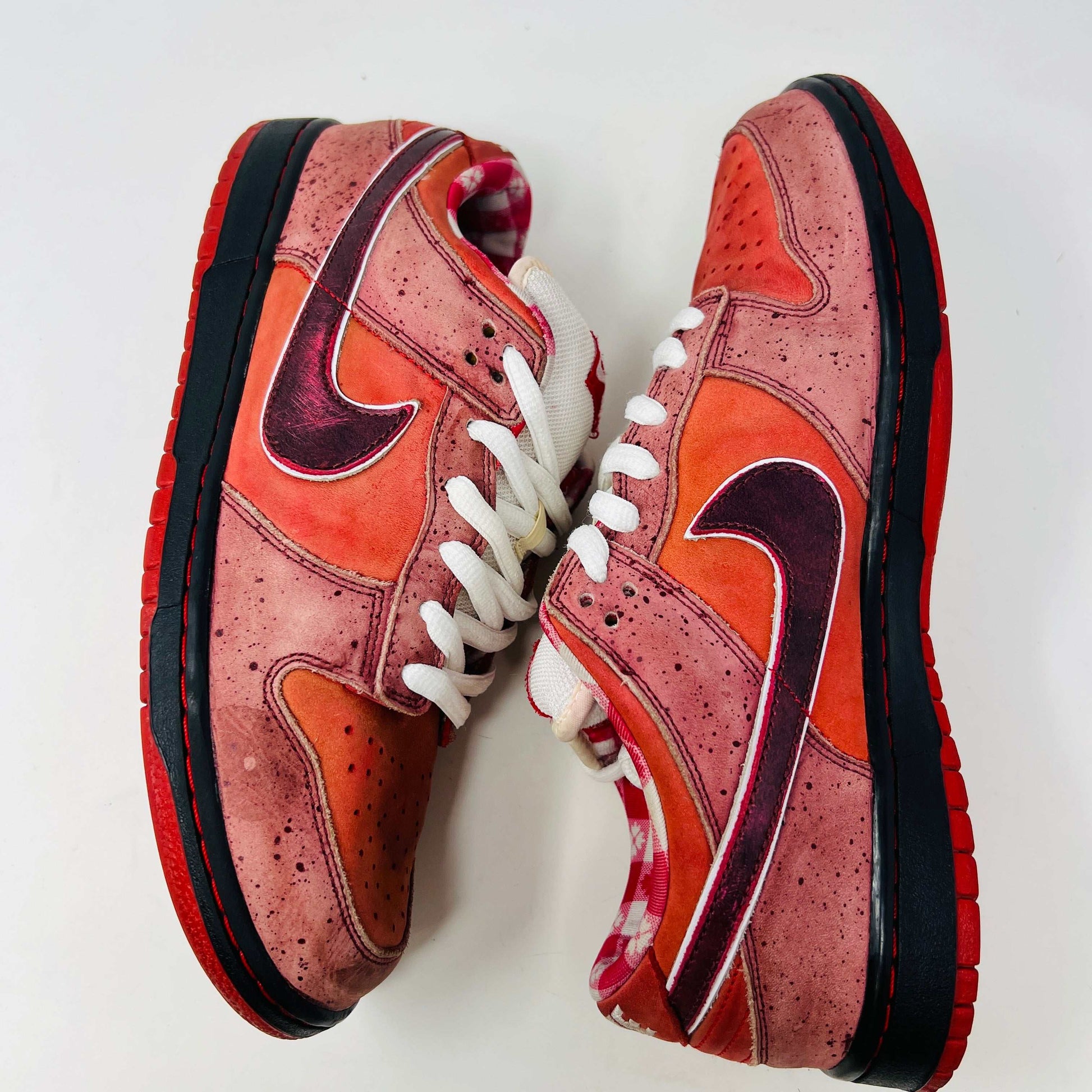 The authentic 2008 Nike SB Dunk Low Concepts Red Lobster features a striking red and pink design with a dark swoosh, complemented by white laces and red accents. It comes in a speckled gray and black replacement box for added flair.