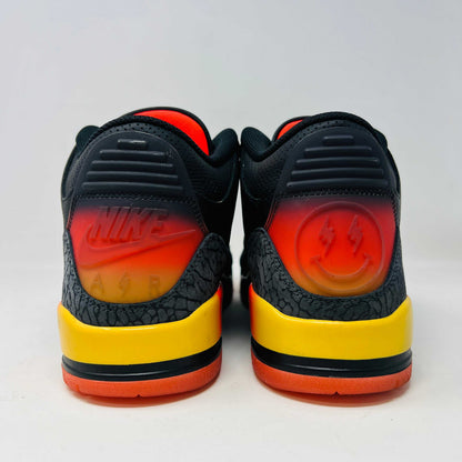 The Jordan 3 Retro J Balvin Rio sneaker in black features clean uppers and textured details with a vibrant gradient heel. It comes atop a box with a black and orange sunset design, accompanied by bright orange laces, ensuring authenticity.