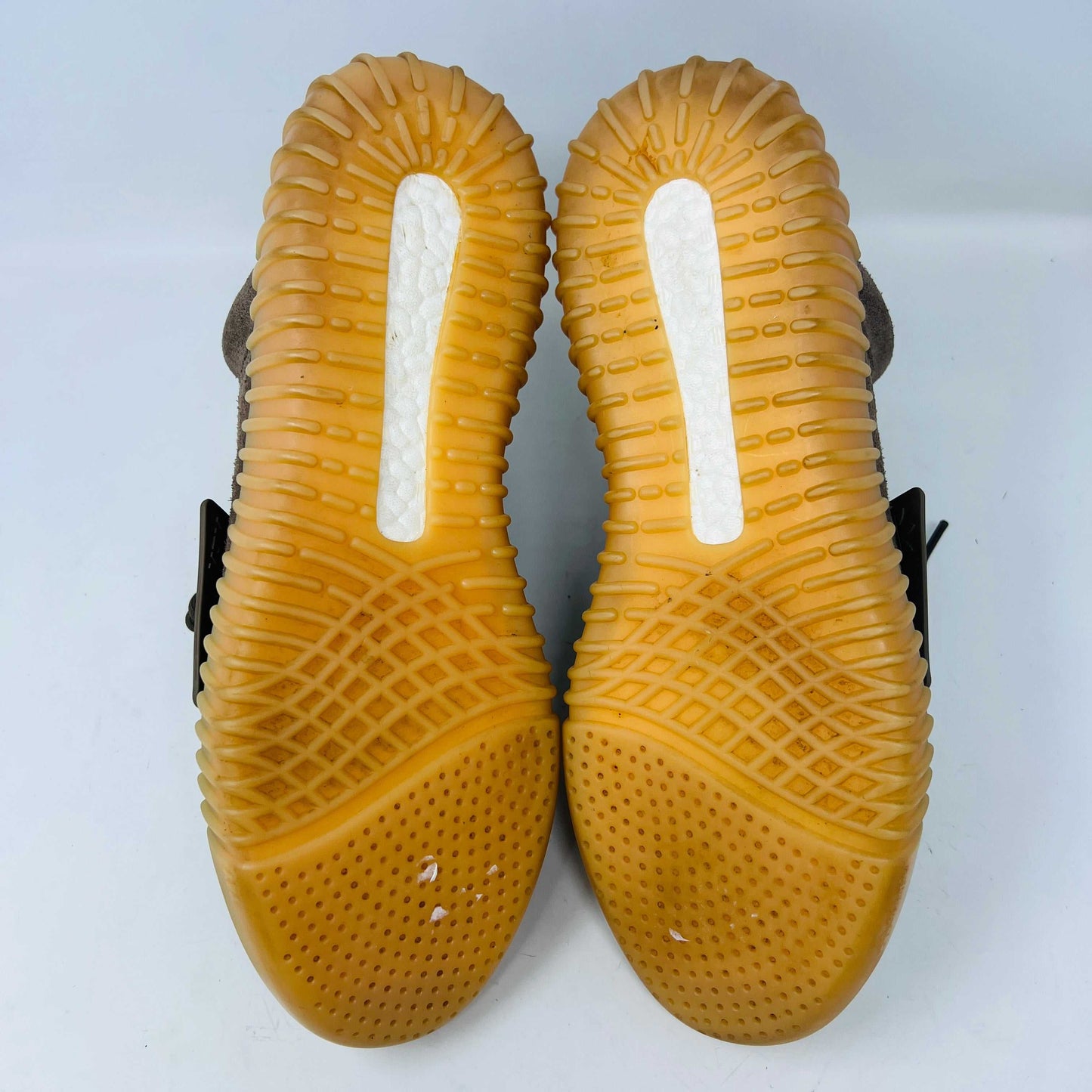 The adidas Yeezy Boost 750 Chocolate sneakers, designed by Yeezy, feature brown suede high-tops with clean uppers and thick ribbed soles. A wide elastic strap and tied laces enhance the sleek look, set against a plain white backdrop. Available on final sale.