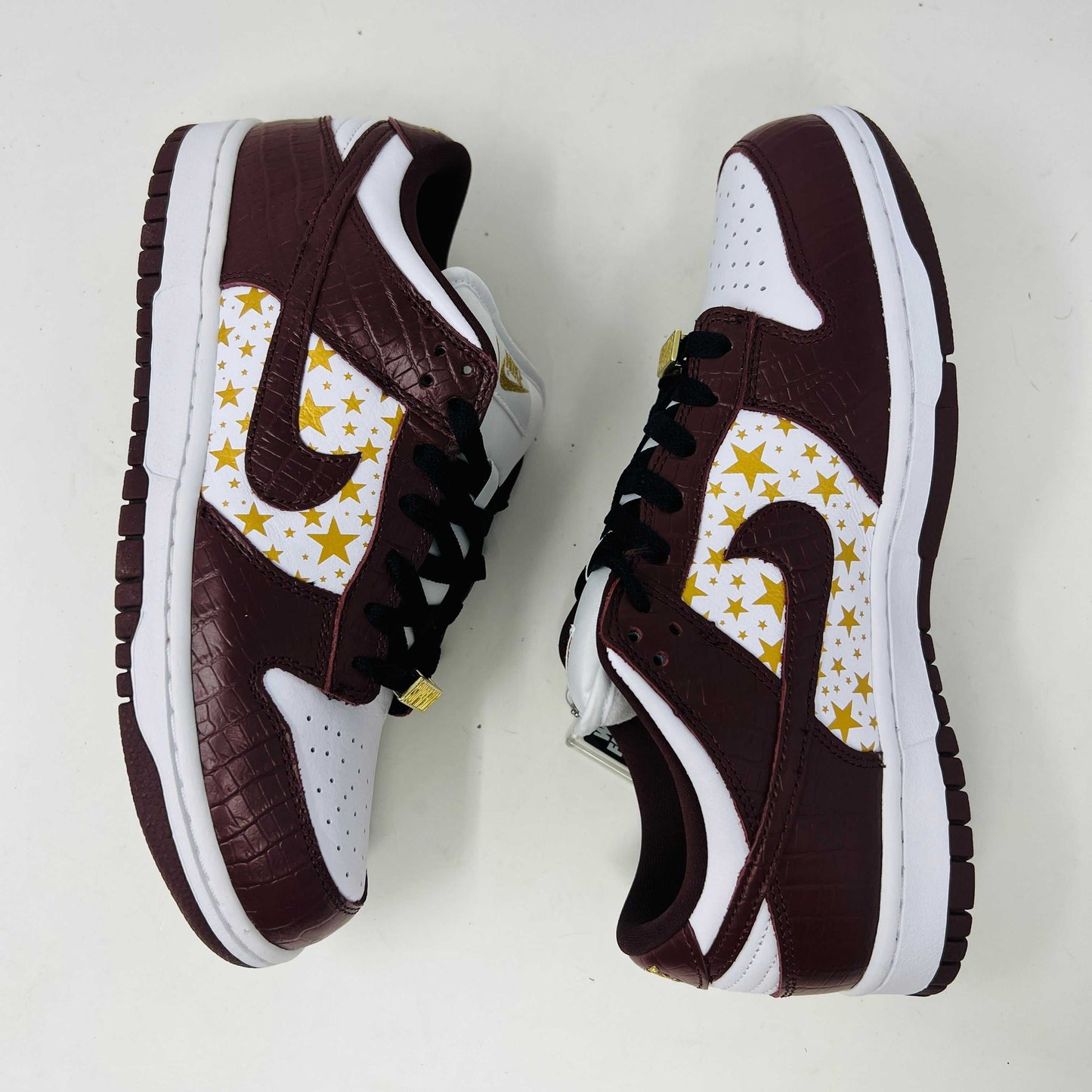 Introducing the new Nike SB Dunk Low Supreme Barkroot sneakers by Nike, featuring a star pattern with a World Famous Supreme tag and housed in a striking purple Nike SB box.