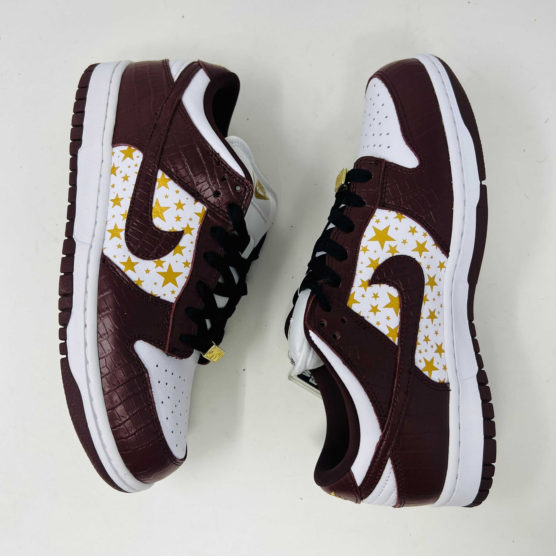 Introducing the new Nike SB Dunk Low Supreme Barkroot sneakers by Nike, featuring a star pattern with a World Famous Supreme tag and housed in a striking purple Nike SB box.