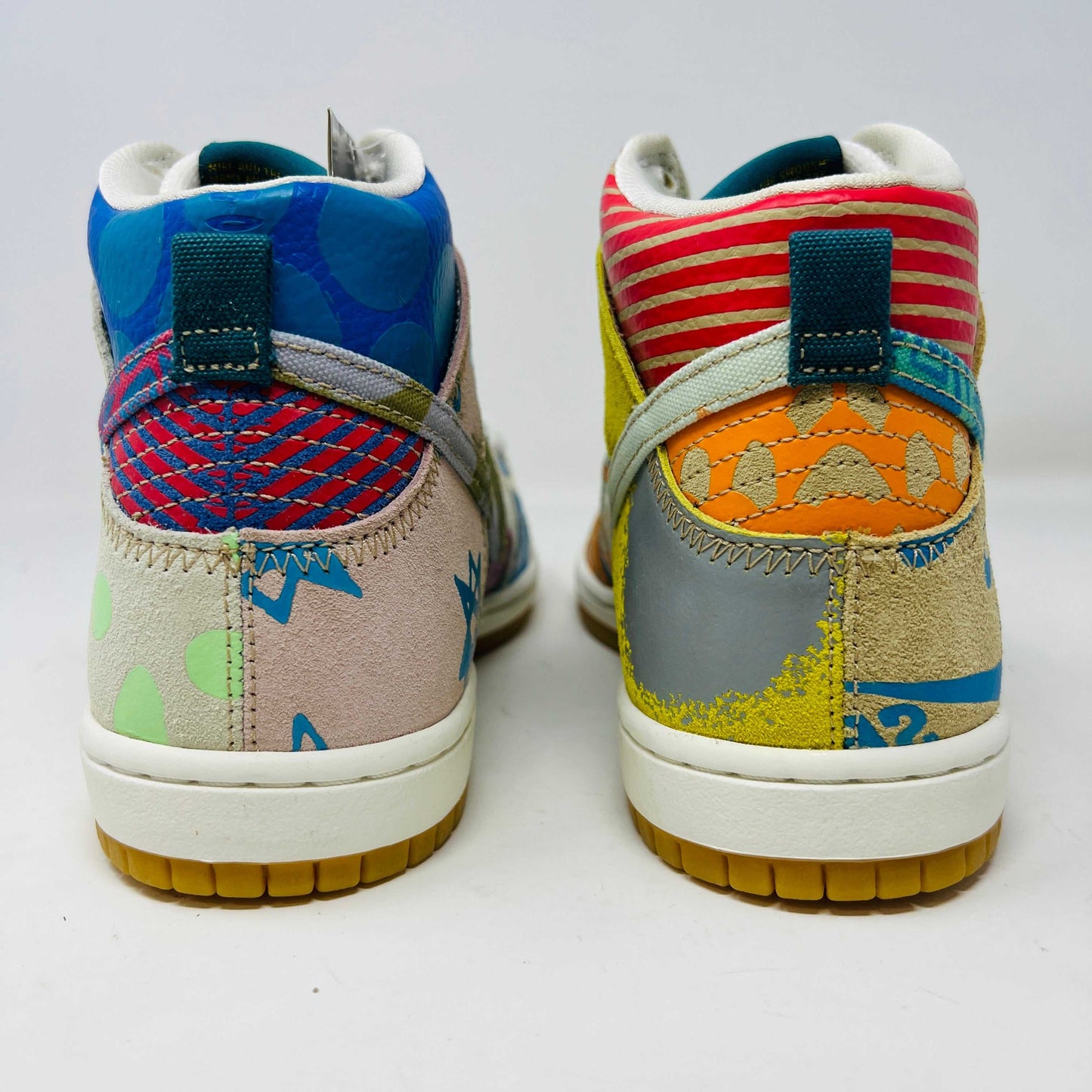 The Nike SB Dunk High Thomas Campbell What The Dunk, a colorful high-top sneaker, features a mix of patterns and textures with a blue Nike logo. It is on a teal SB box, BRAND NEW and 100% Authentic. An orange lace lies beside this shoe featuring blue, green, pink, and tan elements.