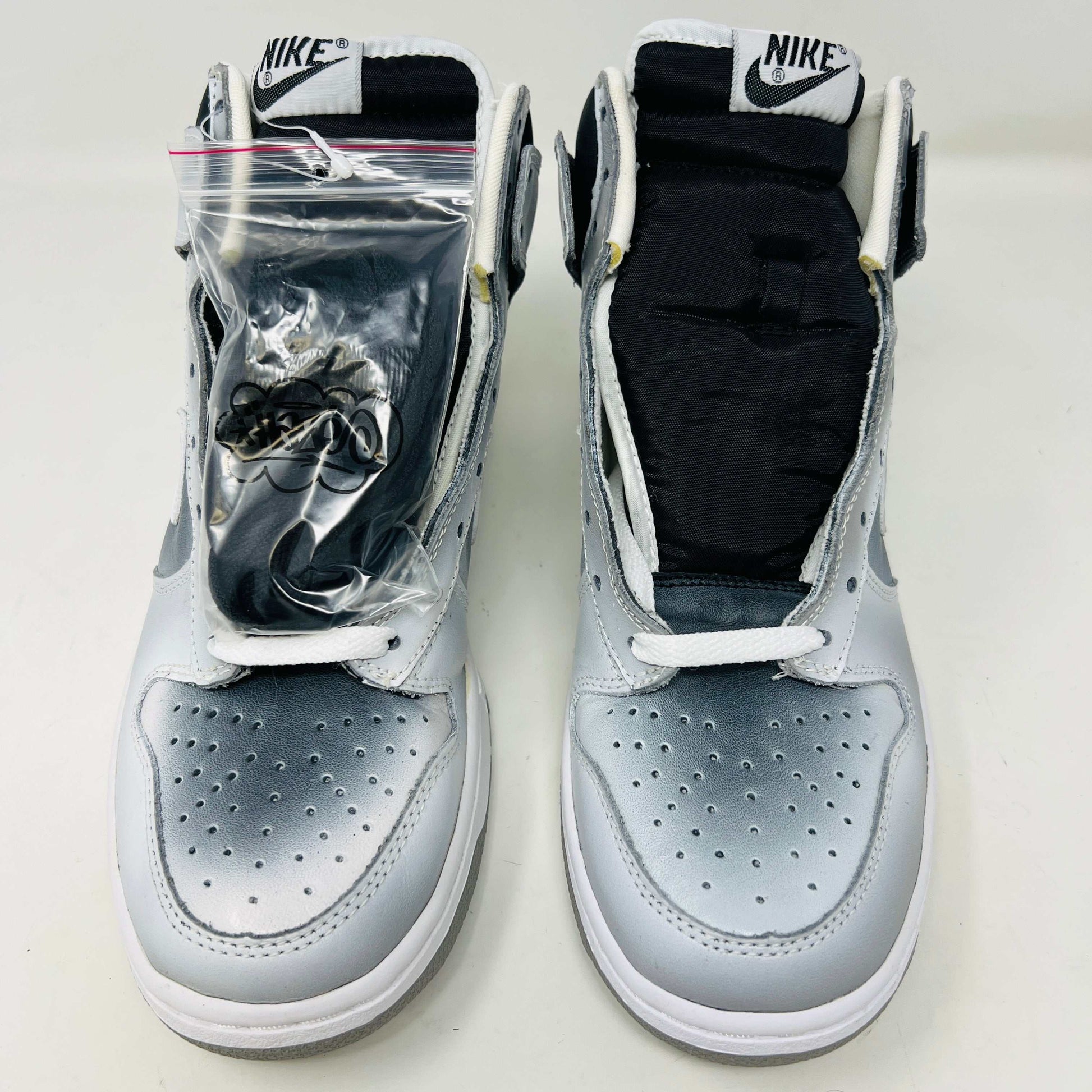 The Nike Dunk High Haze, a brand new and 100% authentic high-top sneaker, showcases a gray and white color scheme with a prominent swoosh and textured sole. It rests on an orange box with the Nike logo, set against a plain white background.