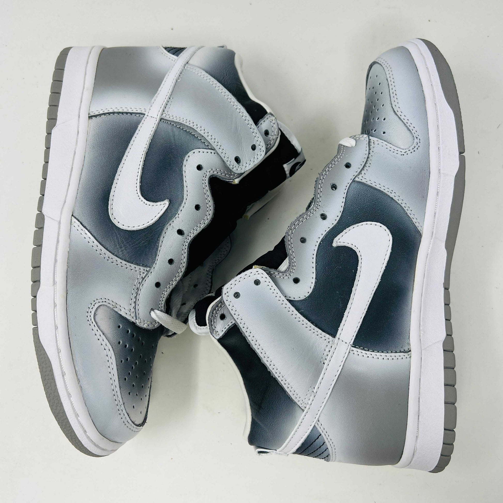 The Nike Dunk High Haze, a brand new and 100% authentic high-top sneaker, showcases a gray and white color scheme with a prominent swoosh and textured sole. It rests on an orange box with the Nike logo, set against a plain white background.