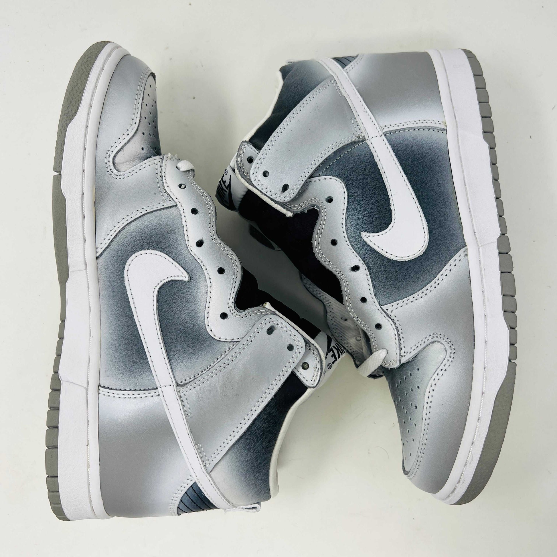 The Nike Dunk High Haze, a brand new and 100% authentic high-top sneaker, showcases a gray and white color scheme with a prominent swoosh and textured sole. It rests on an orange box with the Nike logo, set against a plain white background.