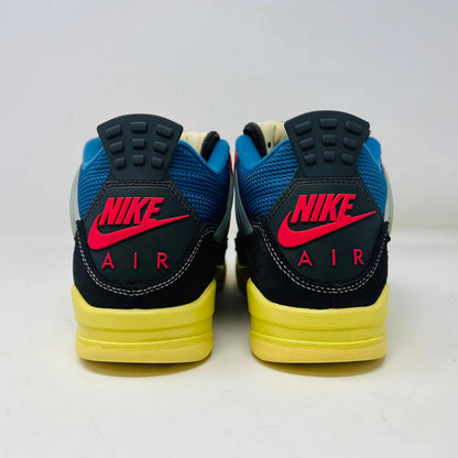 Displayed on their box, the 100% authentic Jordan 4 Retro Union Off Noir sneakers from the Jordan brand showcase clean black uppers, a yellow sole, blue accents, and feature a clear hang tag with a white Jumpman logo. Yellow extra laces are also placed on the box.