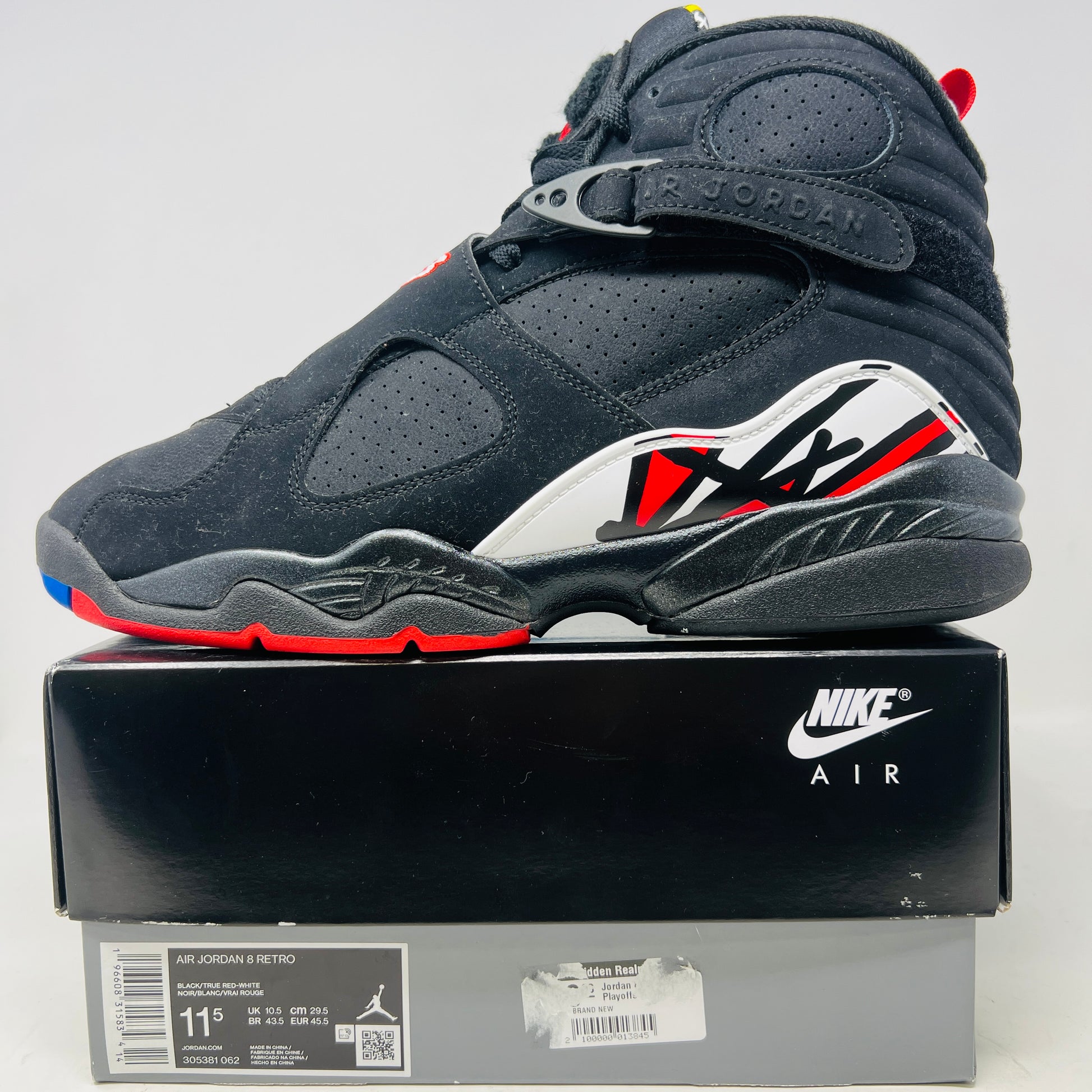 A Jordan 8 Retro Playoffs (2023) shoe, black and red with gray/red accents, features a high-top design with a strap, textured sole with blue hints, and clean uppers. Displayed on its Nike Air box in good condition, the label reveals size and Jordan brand details.