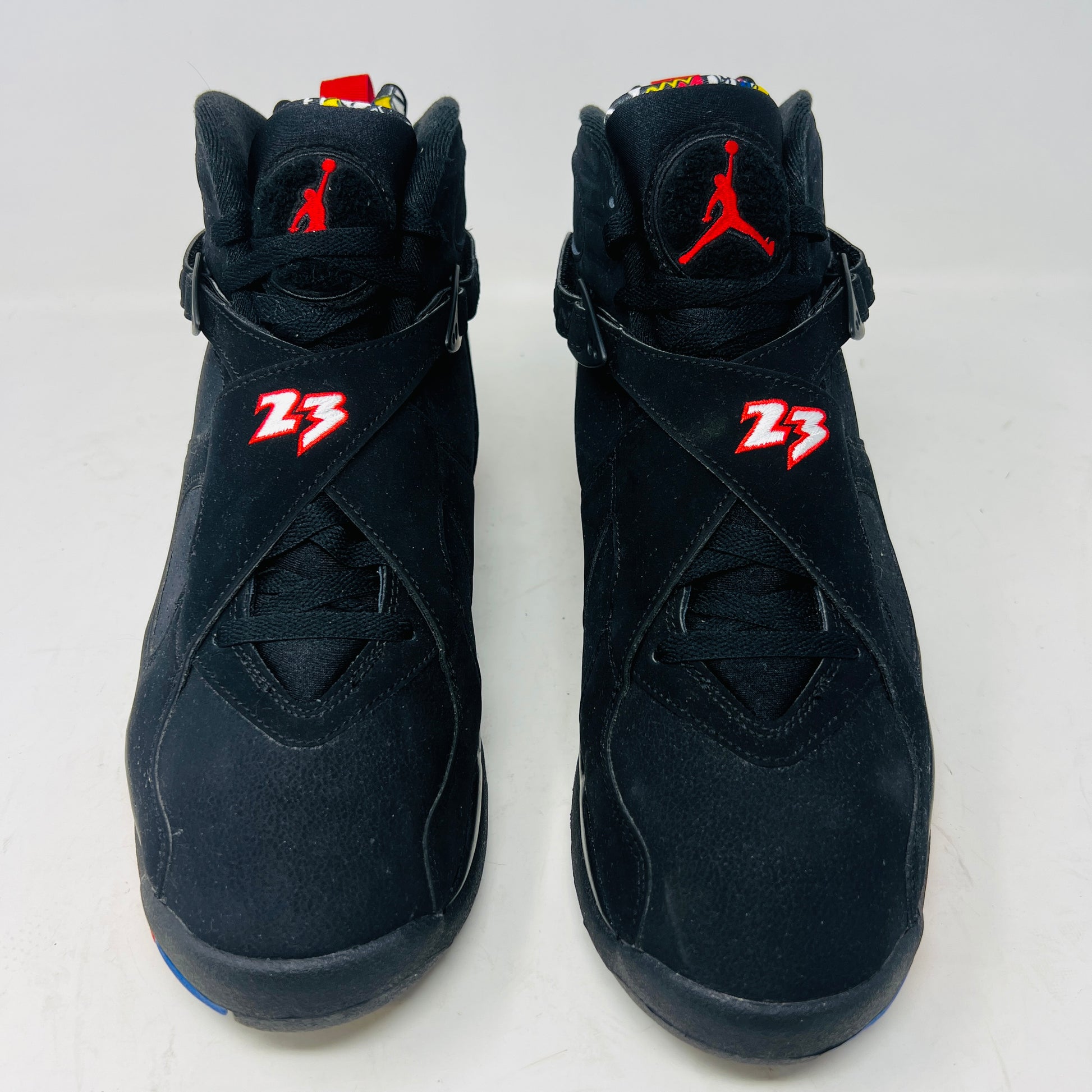 A Jordan 8 Retro Playoffs (2023) shoe, black and red with gray/red accents, features a high-top design with a strap, textured sole with blue hints, and clean uppers. Displayed on its Nike Air box in good condition, the label reveals size and Jordan brand details.