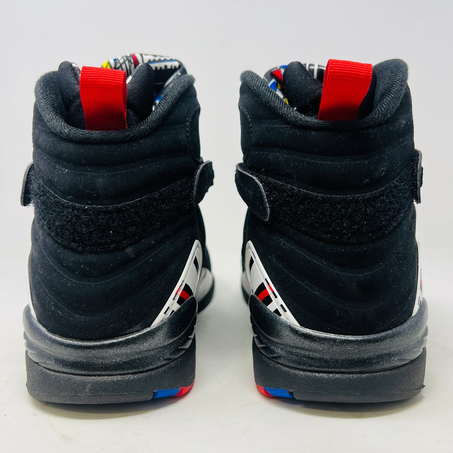 A Jordan 8 Retro Playoffs (2023) shoe, black and red with gray/red accents, features a high-top design with a strap, textured sole with blue hints, and clean uppers. Displayed on its Nike Air box in good condition, the label reveals size and Jordan brand details.