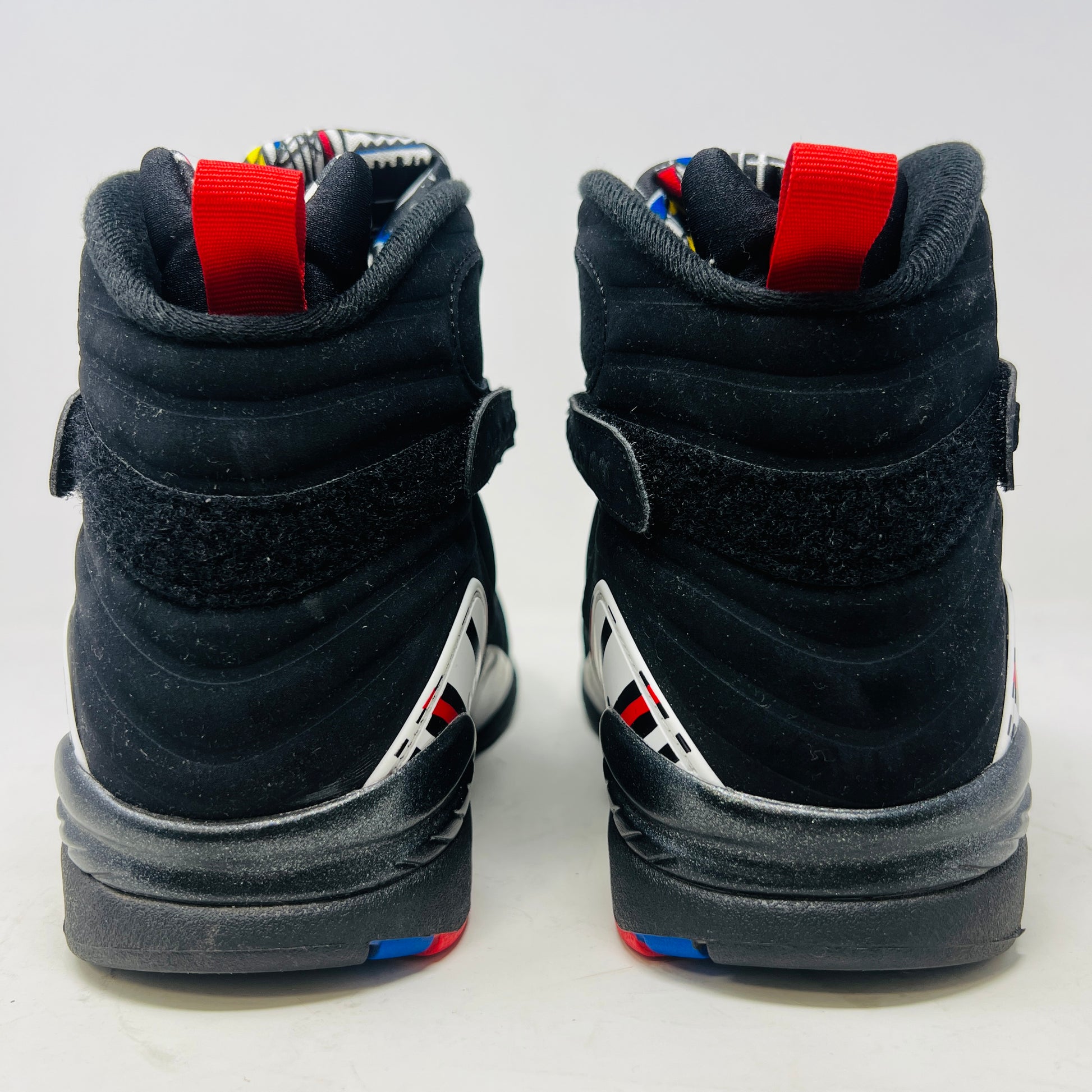 A Jordan 8 Retro Playoffs (2023) shoe, black and red with gray/red accents, features a high-top design with a strap, textured sole with blue hints, and clean uppers. Displayed on its Nike Air box in good condition, the label reveals size and Jordan brand details.