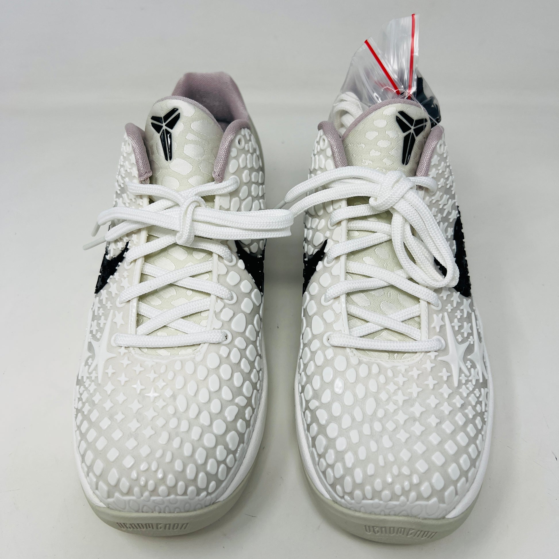 The fresh white Nike Kobe 6 Sail All-Star (GS) athletic shoe, showcasing a textured design and black swoosh logo, is presented on an orange box. Inside are plastic-wrapped accessories and extra laces for versatile style in 2024.