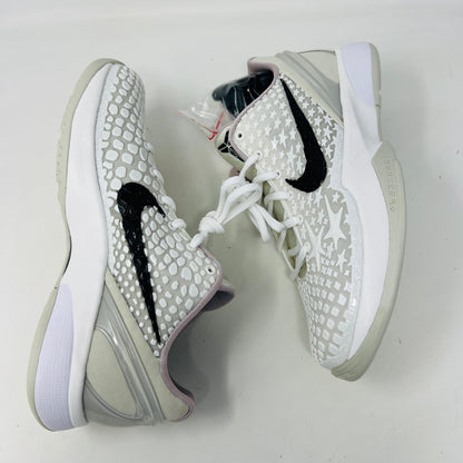 The fresh white Nike Kobe 6 Sail All-Star (GS) athletic shoe, showcasing a textured design and black swoosh logo, is presented on an orange box. Inside are plastic-wrapped accessories and extra laces for versatile style in 2024.